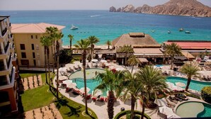 Un complexe hôtelier doté de plusieurs piscines, de palmiers et offrant une vue sur la mer et les montagnes.