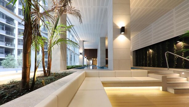A modern indoor space with a central staircase, seating areas, and a water feature.