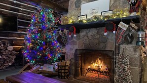 Um quarto aconchegante com lareira de pedra, árvore de Natal e um banco de madeira.
