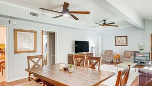 Un'ampia sala da pranzo con tavolo e sedie in legno, una televisione e sedie a motivi decorativi sullo sfondo.