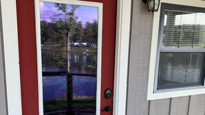 Eine rote Tür mit Fenster, einer Metall-Schutzleiste und einem kleinen Fenster mit Fliegengitter.