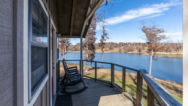 Eine Holzterrasse mit Blick auf einen See und Bäume.