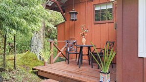 A wooden deck with a table and chairs, surrounded by potted plants and a hanging lantern. - 1 Mile Away from Volcano National Park (Volcano)