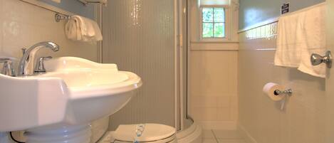 Baño con lavamanos pedestal, inodoro y ducha.