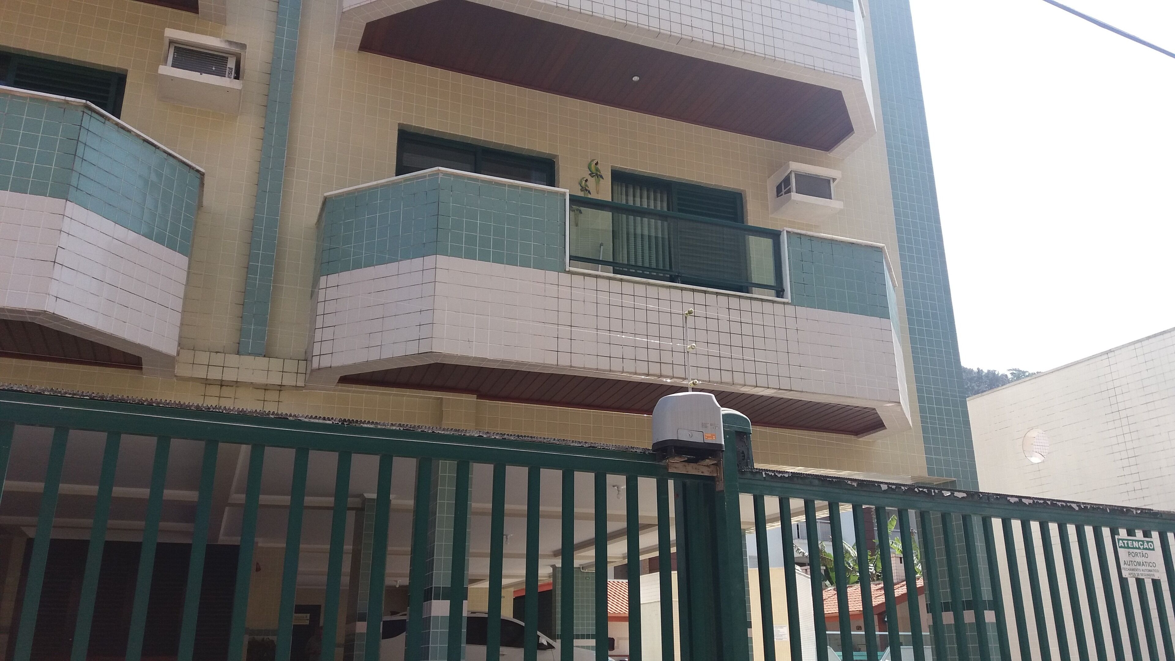 A multi-story building with a green metal fence in the foreground.