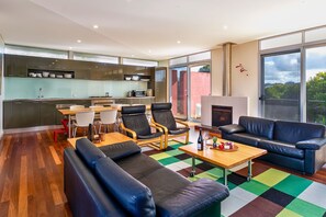 A modern living area with a sofa, chairs, a coffee table, and a fireplace.