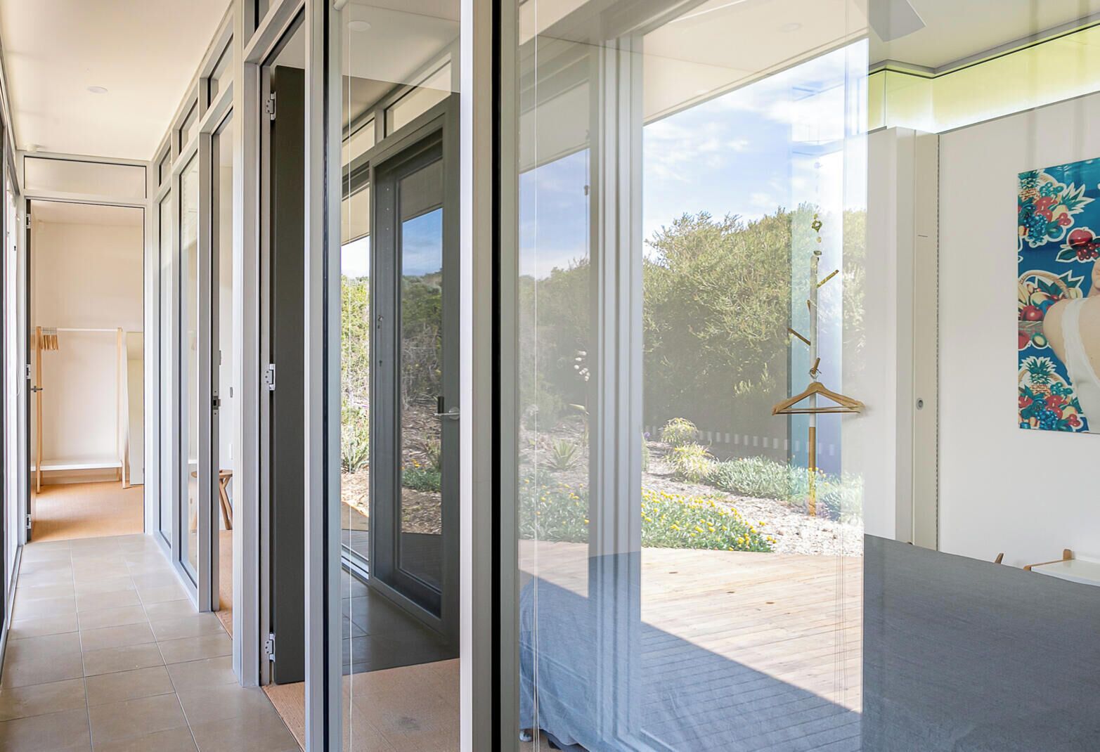 Un couloir moderne avec des portes coulissantes en verre donnant sur un jardin.