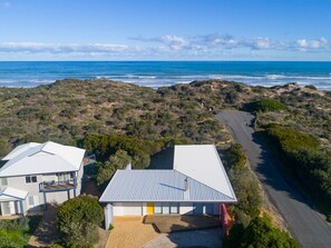 A coastal property with two main buildings, a paved driveway, and a view of the ocean.