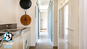 A kitchen with a sink, stove, and washing machine. There is a hallway with doors leading to other rooms.
