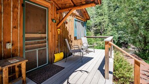 Eine Holzhütte mit einer Veranda, einer Tür und einem Fenster mit Fensterläden.