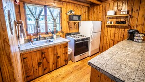 Eine Holzhütte mit Küche, inklusive Spüle, Herd, Kühlschrank und Mikrowelle.