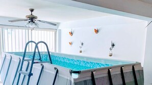 Une piscine intérieure avec un escalier, entourée de murs blancs et dotée d’un sol carrelé.
