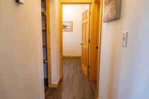Un pasillo estrecho con puertas de madera y un cuadro en la pared.