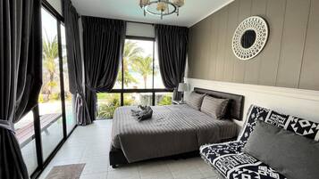A bedroom with a bed, a sofa, a chandelier, a window with curtains, and a view of the outdoors.