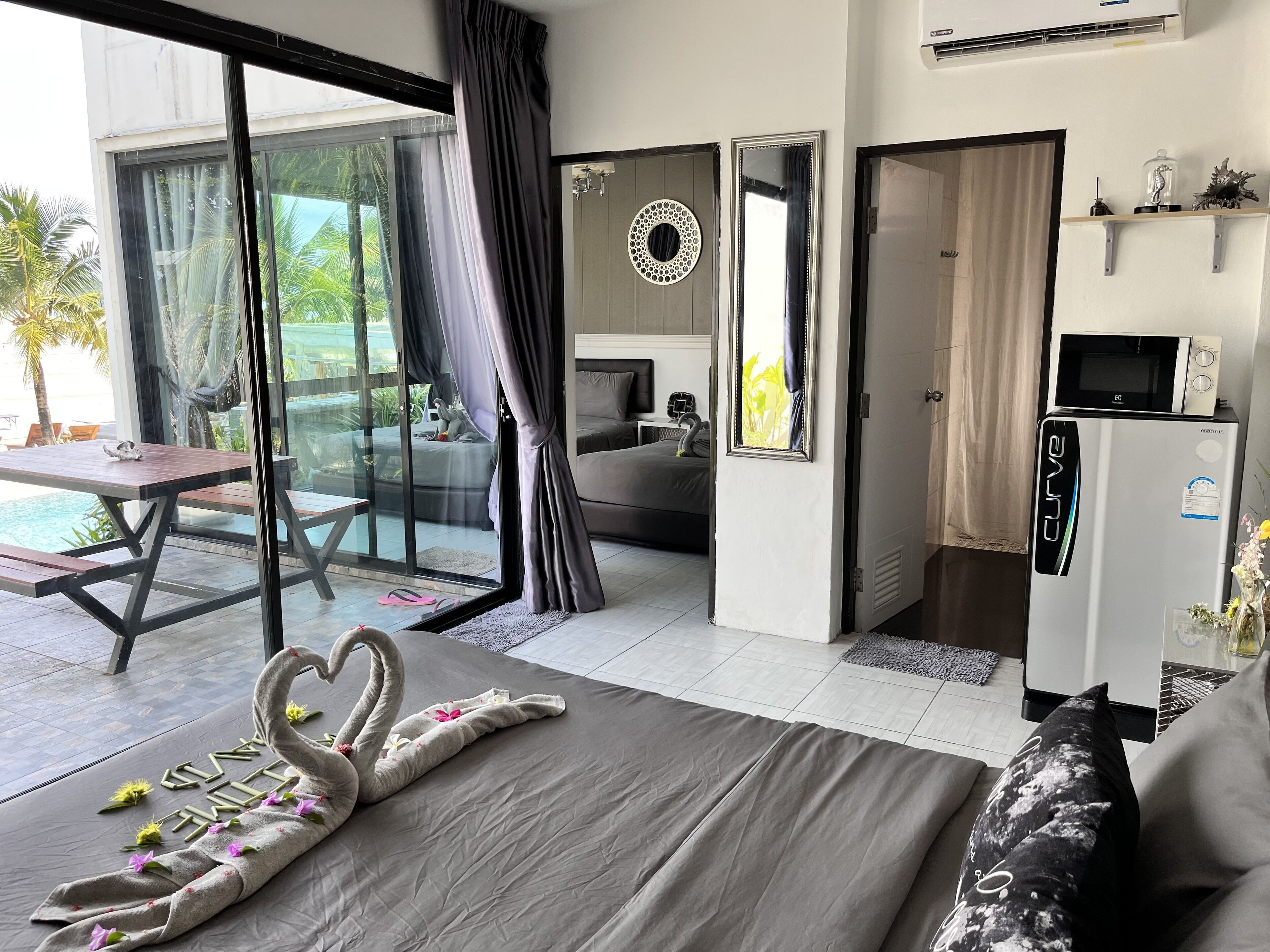 A hotel room with a bed, a dining table, a sofa, a microwave, and a refrigerator.