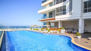 A modern hotel with a large swimming pool, outdoor seating, and a view of the ocean. - SUPERIOR APARTMENT, 1 BEDROOM - 70 METERS LARGE (Santa Marta)