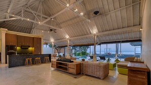 A spacious open-plan living area with a kitchen, bar stools, and a seating area with a view of the ocean.