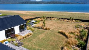 Una casa moderna con terraza, piscina y vistas a un lago y montañas.