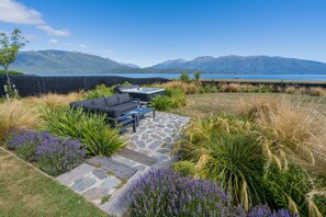 A patio with outdoor furniture, a stone pathway, and a view of mountains and a lake. - Lake House - Te Anau Holiday Home (Te Anau)