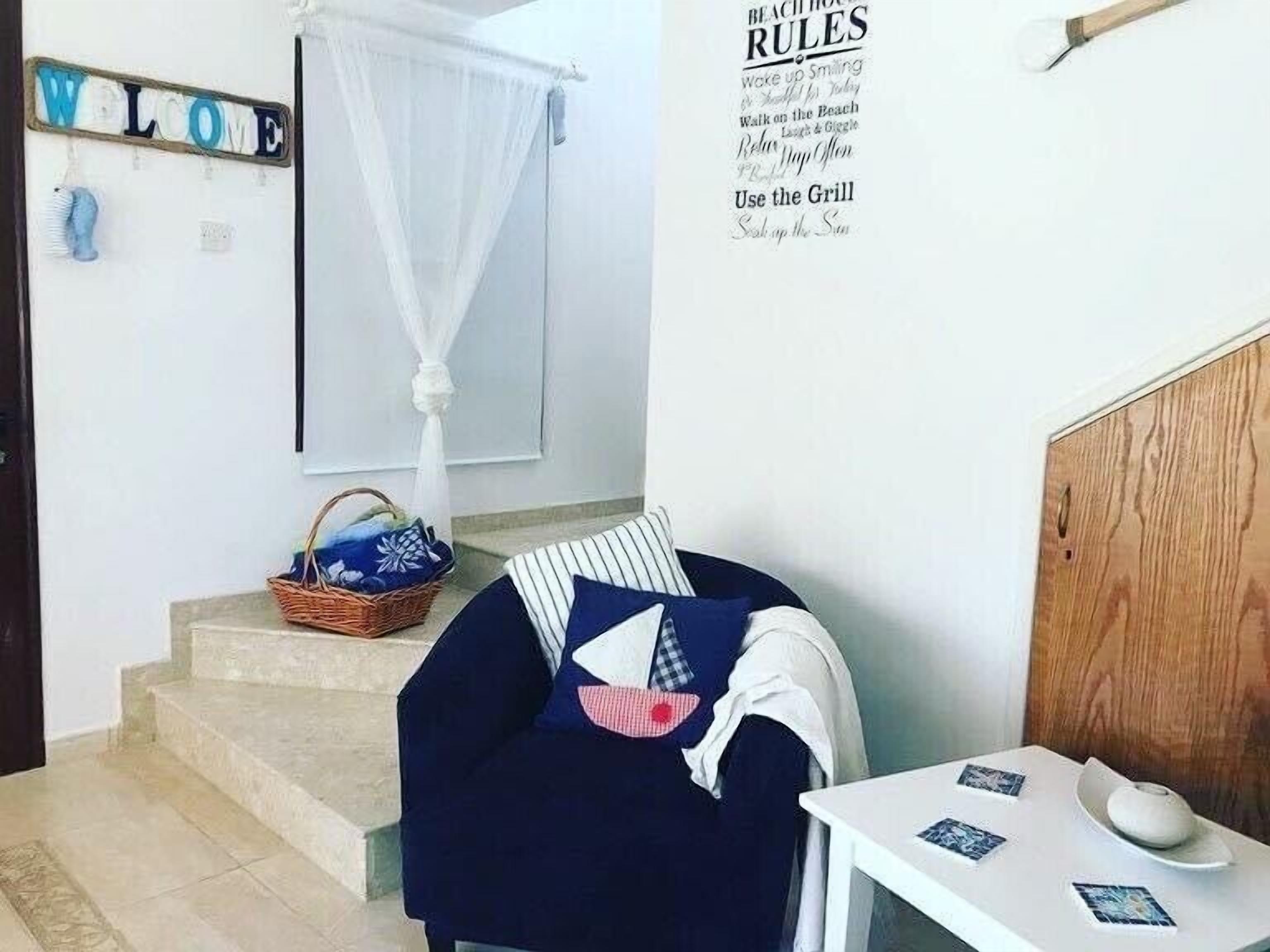 Ett rum med en säng, ett litet bord, en korg och en vägg med en välkomstskylt och en lista över regler.
