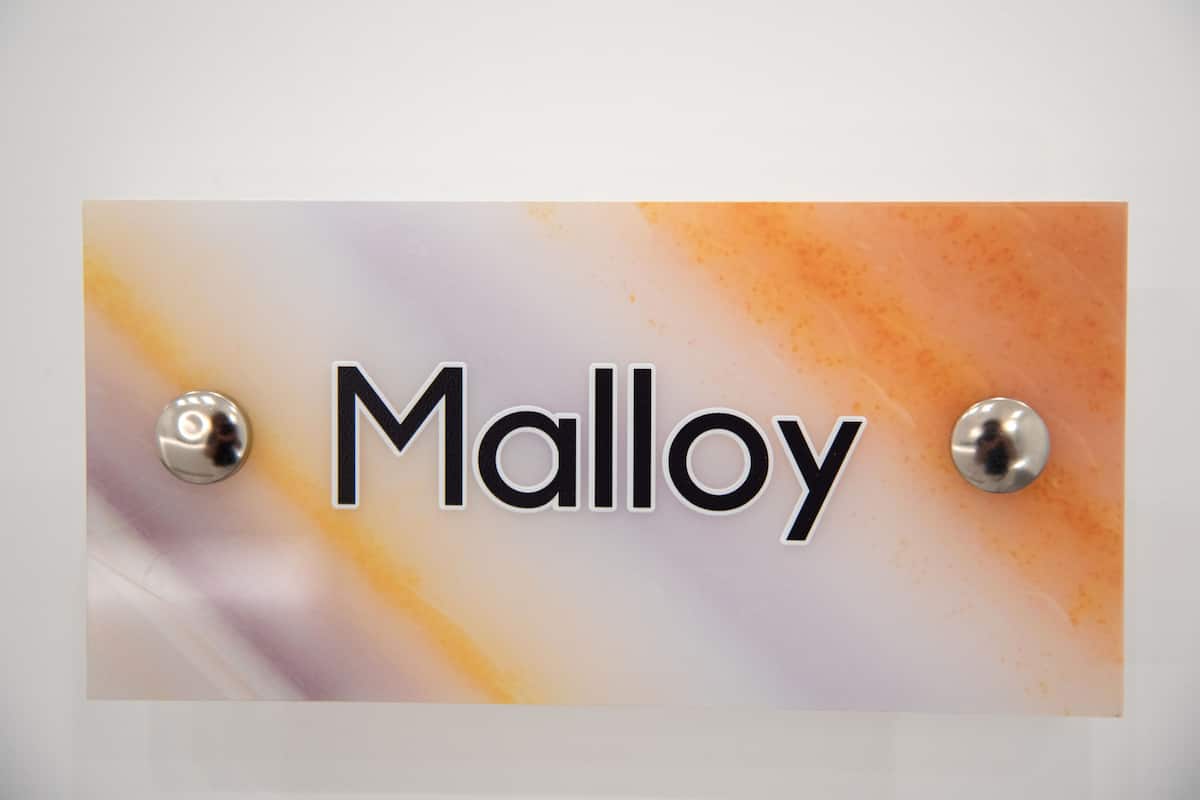 A nameplate with the name "Malloy" mounted on a wall.