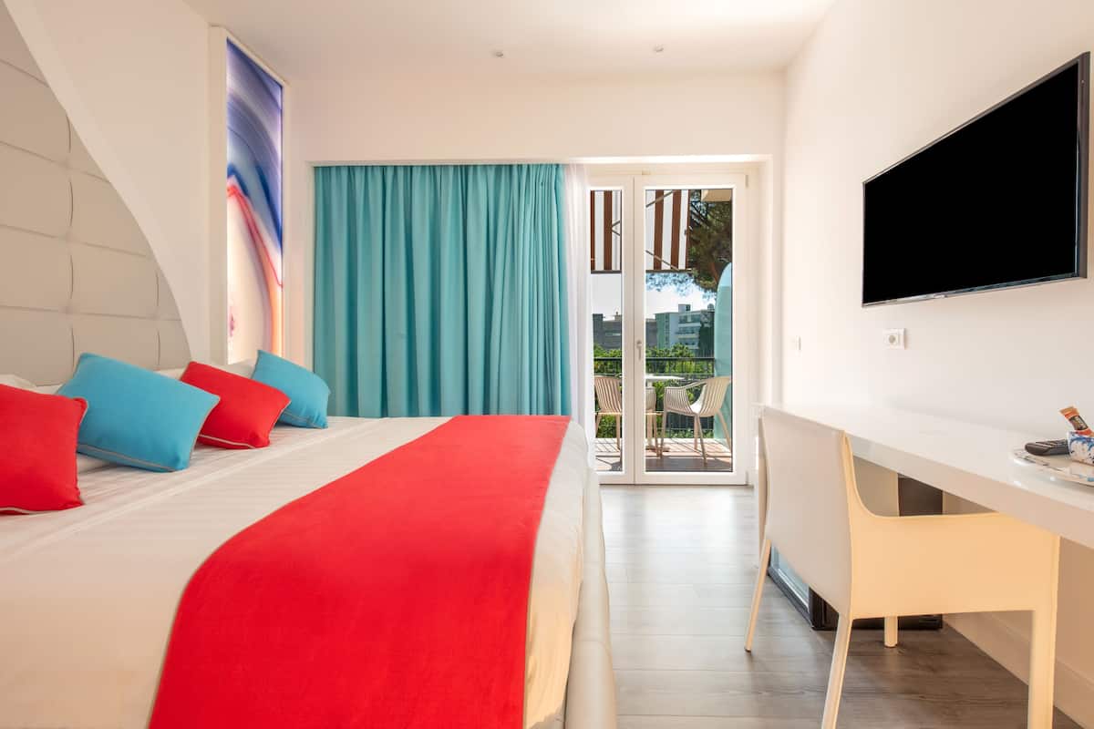 A modern hotel room with a bed, a desk, and a TV.