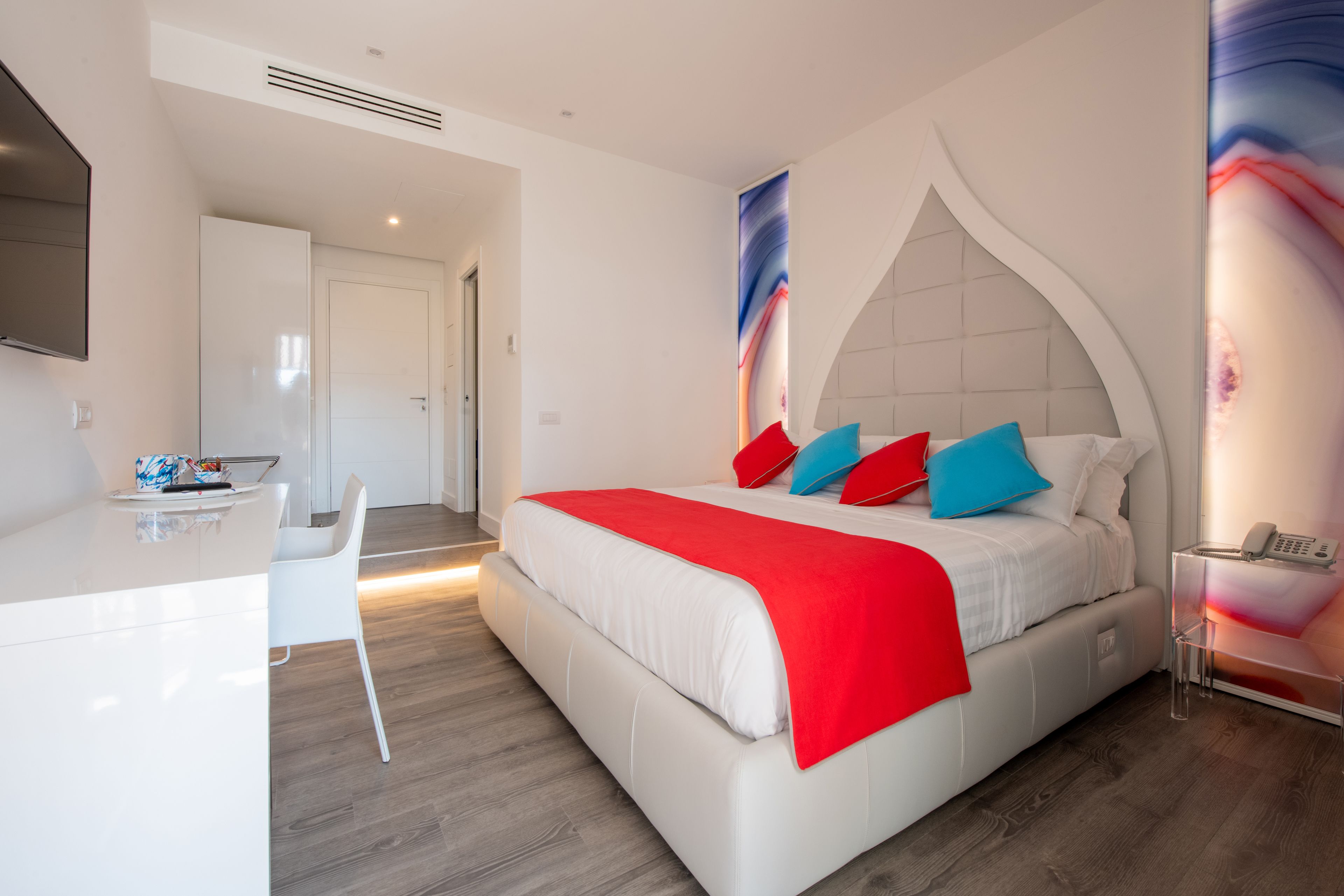A modern bedroom with a large bed, a desk, and a chair.
