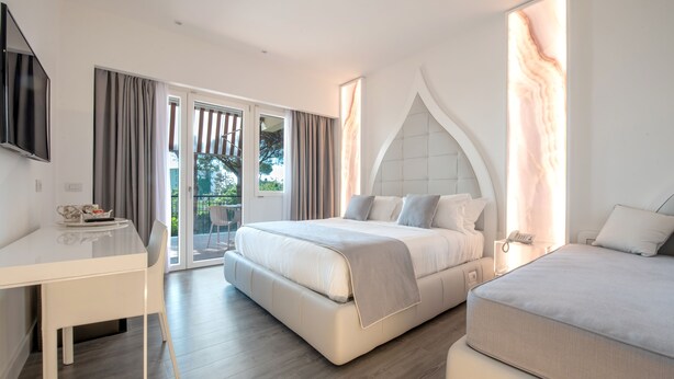 Una camera d'albergo moderna con un letto, una scrivania e un balcone.