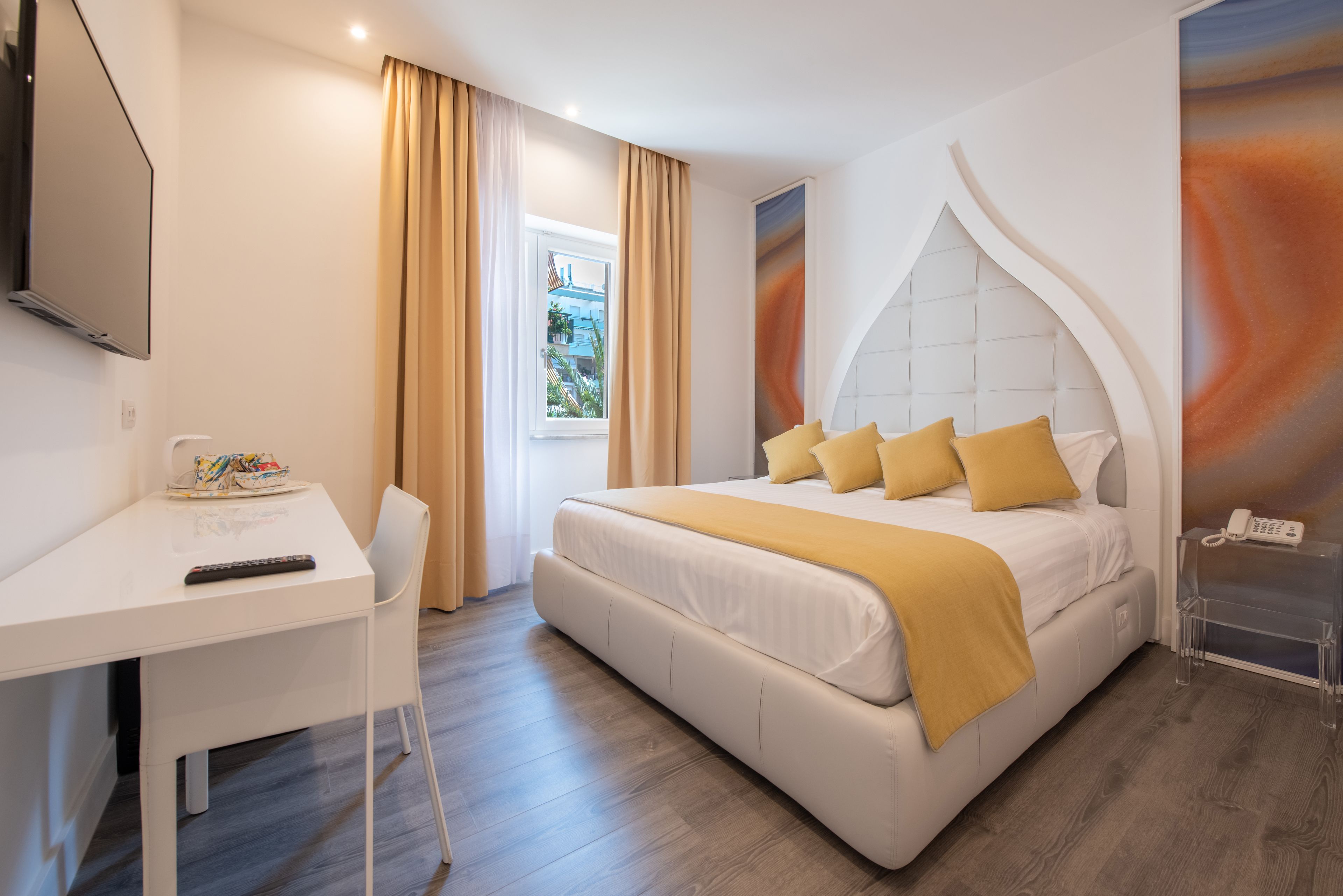 A modern hotel room with a bed, a desk, a chair, and a TV.
