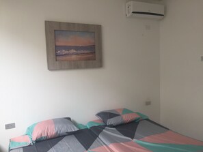 Simple, functional room with a single bed and a framed painting above.