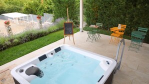 A hot tub in a garden with a table and chairs, surrounded by greenery. - Maralè (Serino)