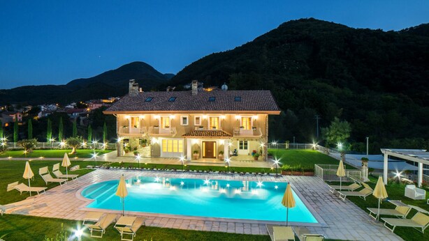 A large house with a swimming pool, surrounded by a well-lit garden and a mountain backdrop. - Maralè (Serino)