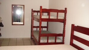 A bunk bed with a wooden frame and a mirror on the wall.