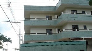A multi-story building with a tiled facade, balconies, and a gated entrance.