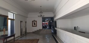 Un pasillo con una araña, una mesa de recepción y una escalera que lleva a un piso superior.
