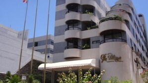 A multi-story hotel with balconies, a clear sky, and flags. - Apartment in Ondina on the carnival circuit (Salvador)