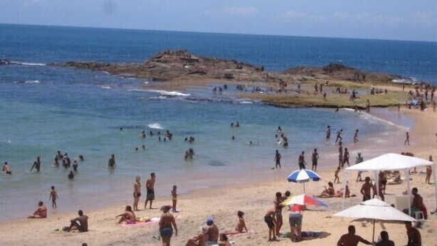 A beach with people swimming and sunbathing, rocky outcrops, and a clear sky. - Apartment in Ondina on the carnival circuit (Salvador)