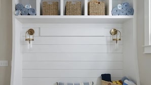 Un banco blanco con cestas de almacenamiento y una cesta tejida.