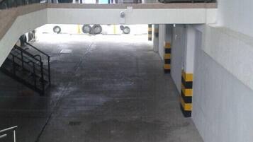 Um espaço interno amplo com piso de concreto, uma escada que leva a uma varanda e um corrimão.