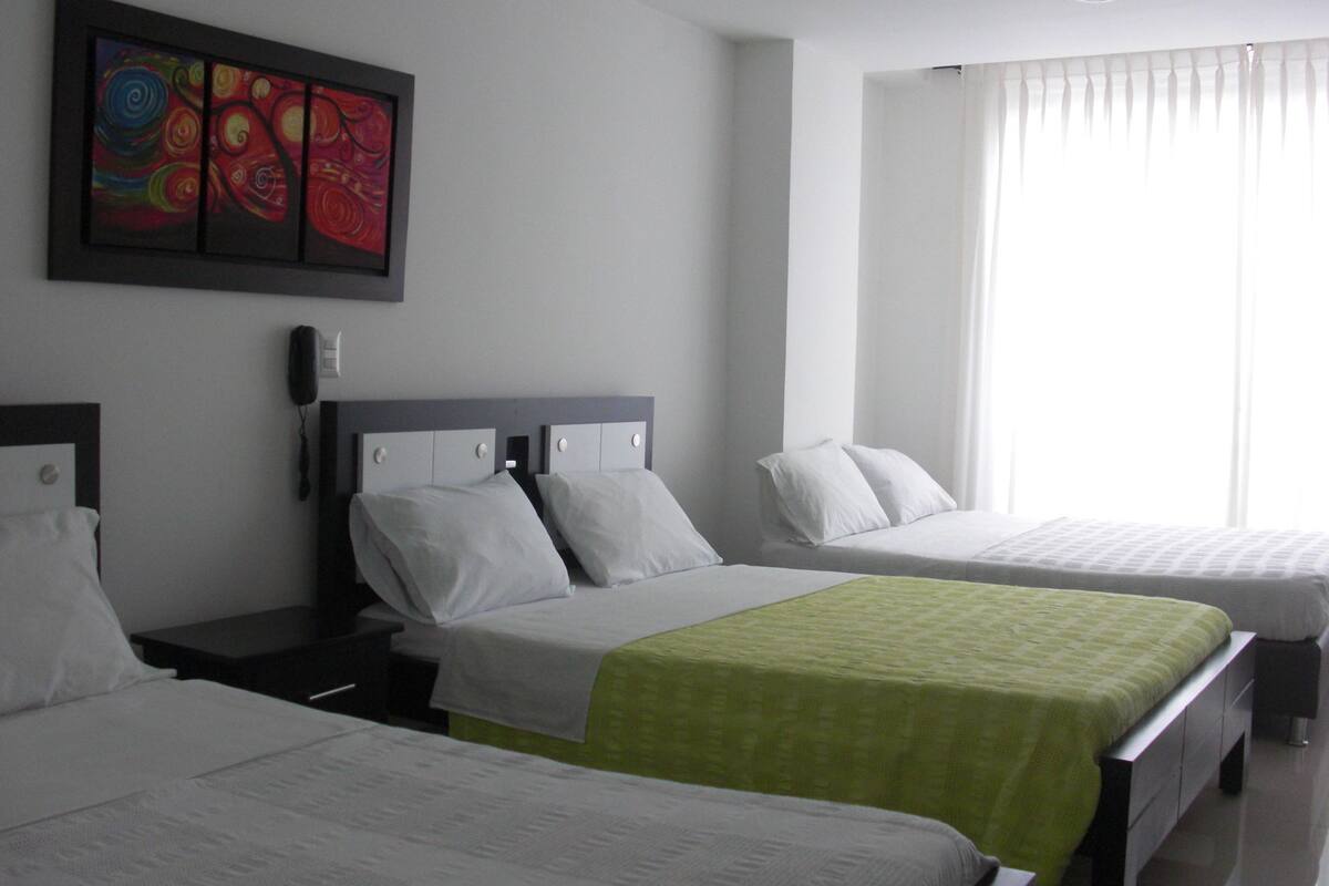 A hotel room with two beds, a painting on the wall, a phone on the nightstand, and a window with curtains.