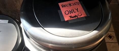 A trash bin with a lid and a note taped to it that reads "RECYCLED ONLY Thanks :)".