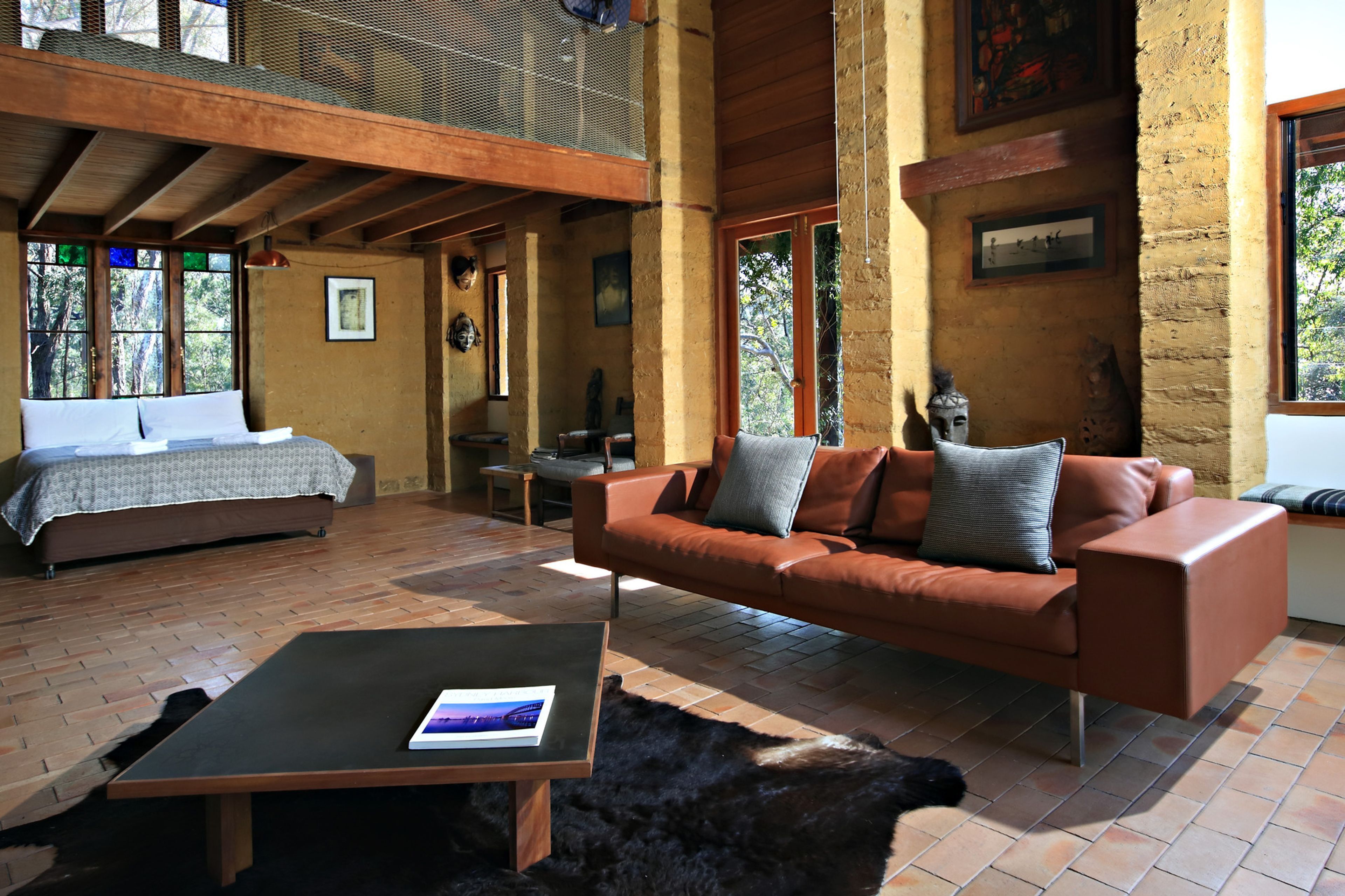 A spacious living area with a bed, a leather sofa, a coffee table, and a fireplace.