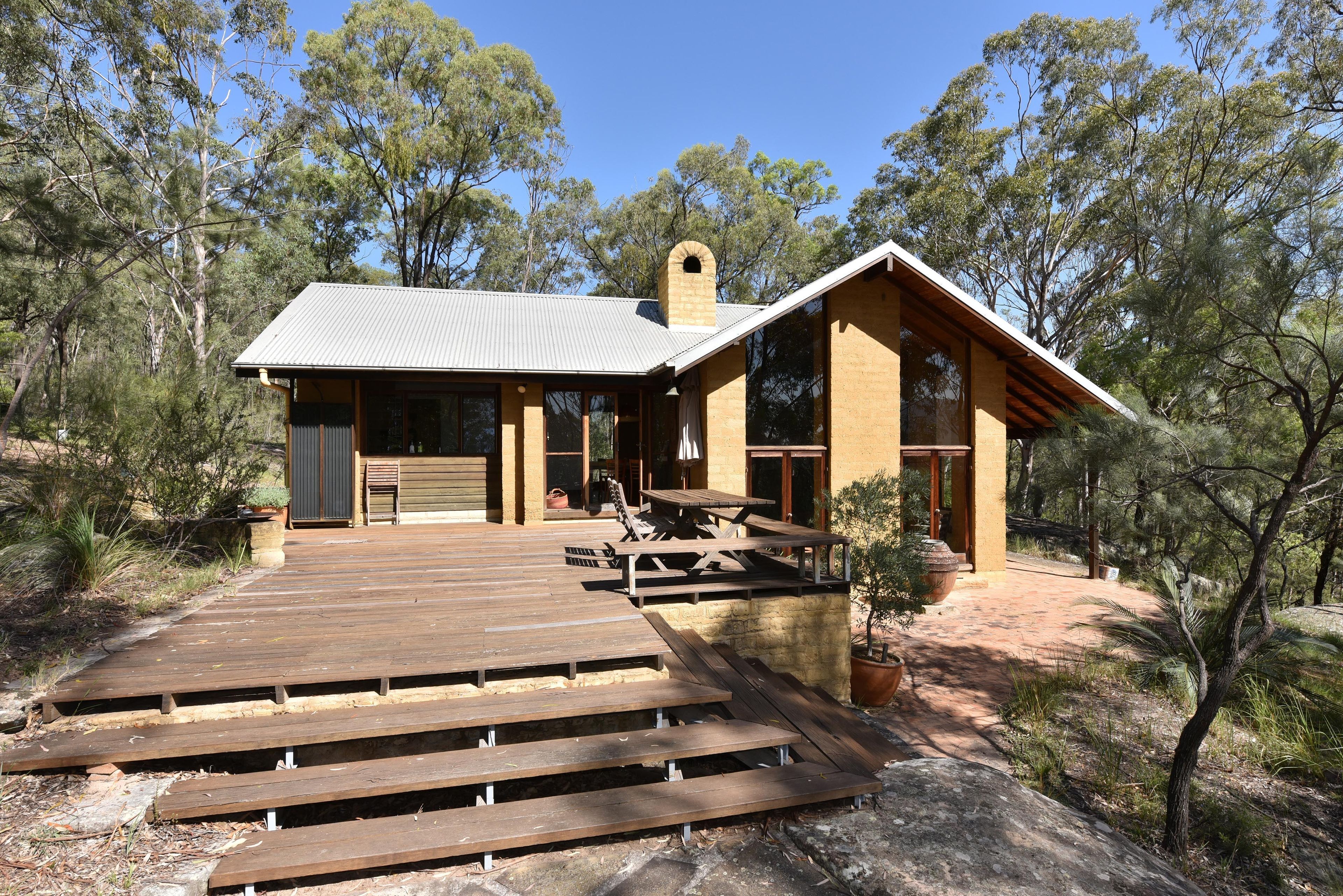 A modern house with a wooden deck, a chimney, and a large window.