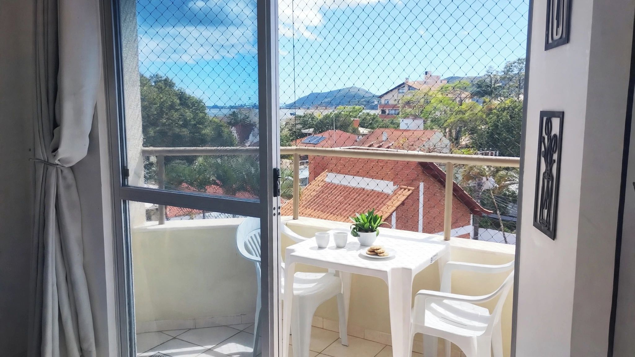 Un balcon avec une table, des chaises et un pot de fleurs.