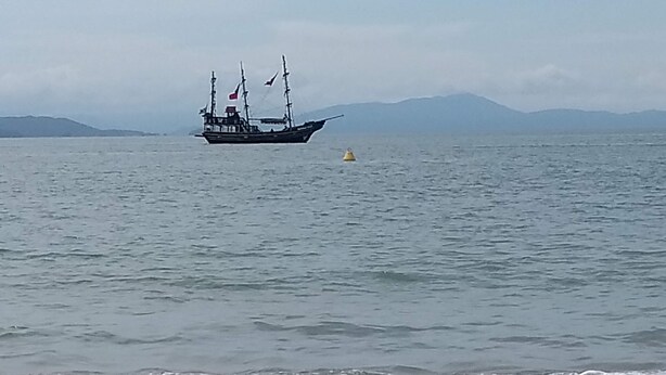 Un bote sobre aguas tranquilas con una costa lejana y montañas.