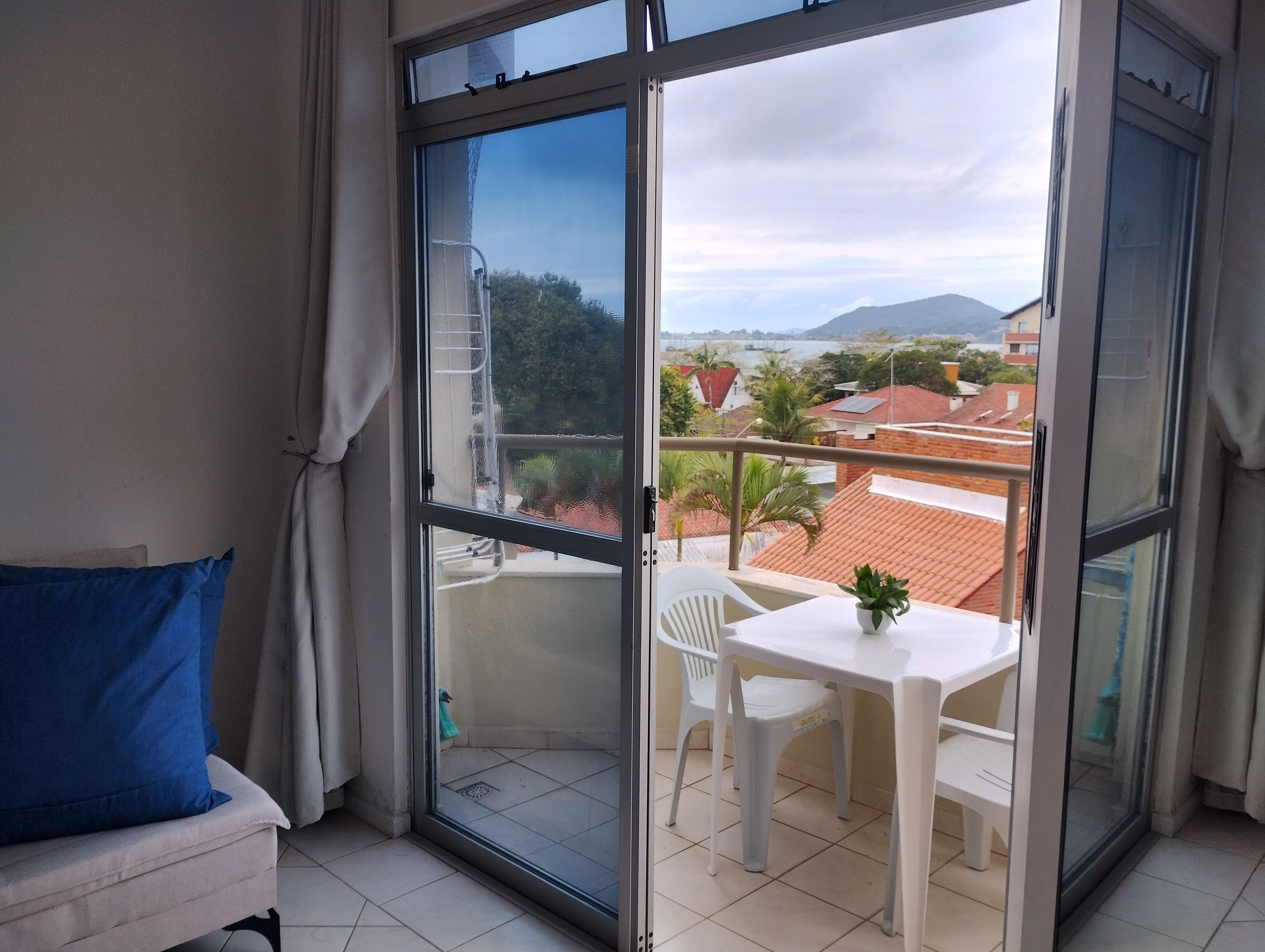 Uma varanda com mesa e cadeiras, vista de edifícios e uma ponte, e uma montanha ao longe.