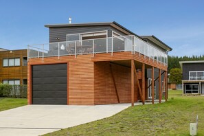 Uma casa moderna de dois andares com garagem, varanda e uma janela grande.