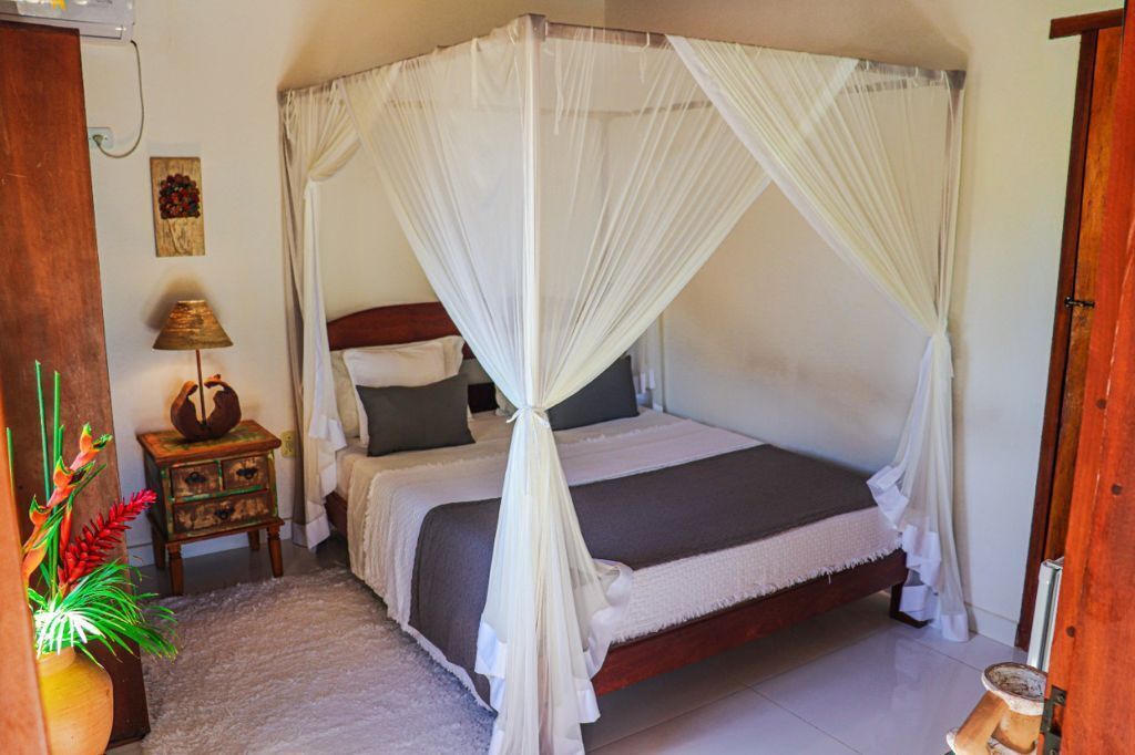 A four-poster canopy bed with a wooden frame and white bedding.