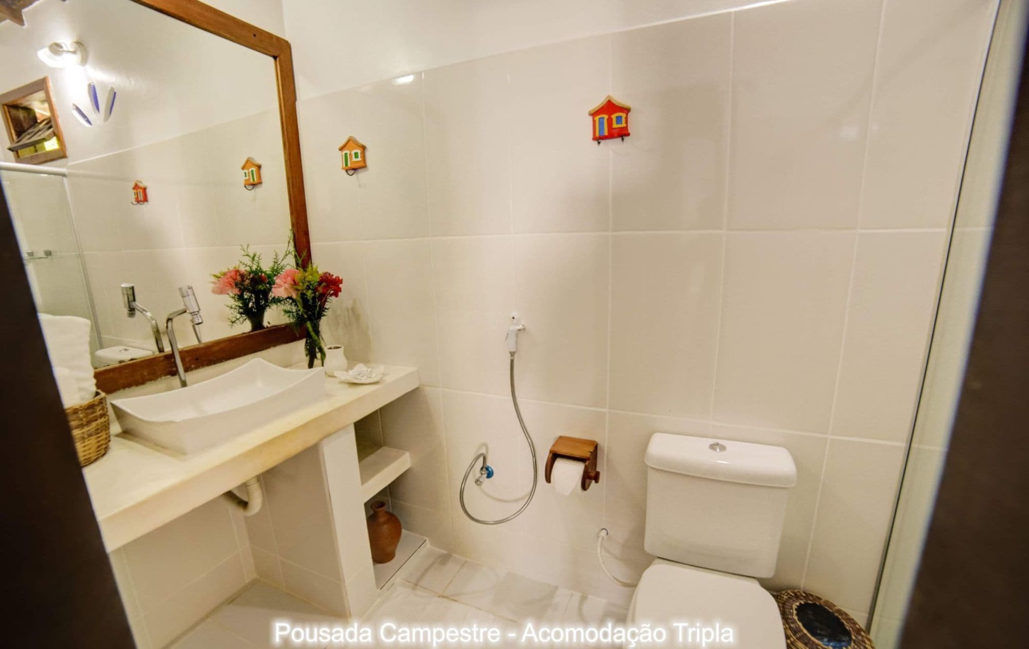 A bathroom with a white sink, mirror, and toilet. There are decorative house-shaped lights on the wall.