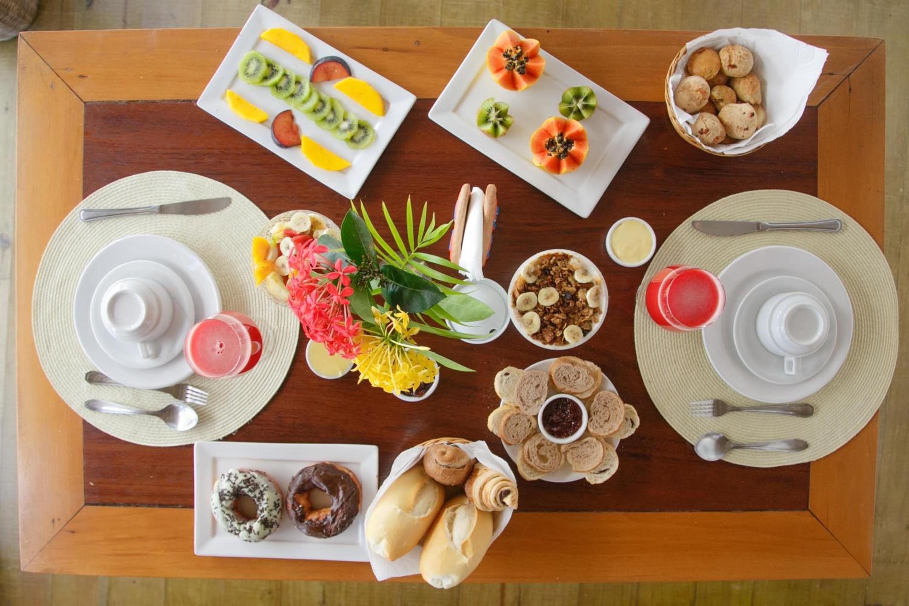 A breakfast buffet with various food items and utensils laid out on a wooden table.